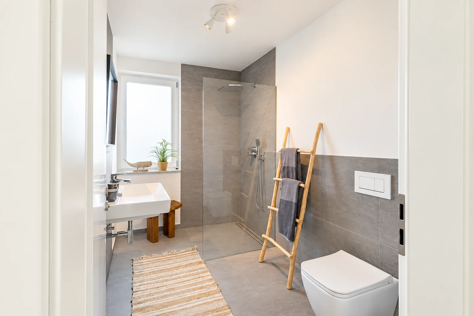 Helles Badezimmer mit grauen Fliesen, Waschtisch und wandhängendem WC